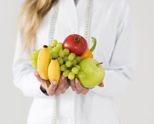 Profesional de la nutrición sosteniendo frutas frescas como parte de una alimentación saludable.